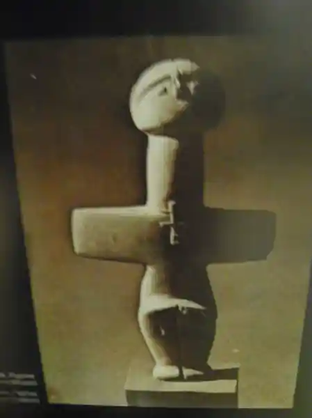 Cross-shaped phalli with face, feet, and a small cross on its chest